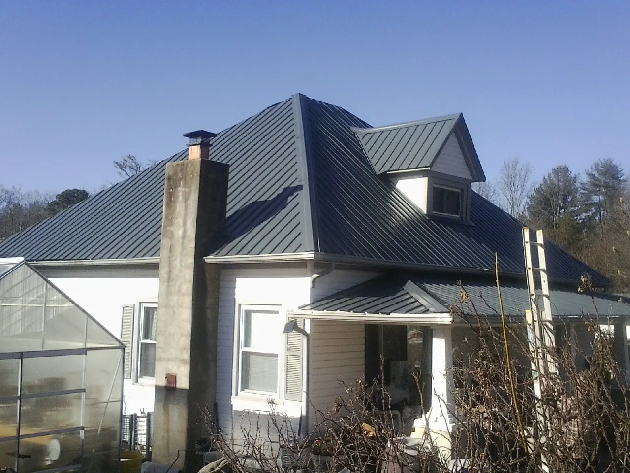Dark blue standing seam metal roof on a white farmhouse with dormer — Slate & Tile Roof Repair by Roofing Brothers in Otterbein