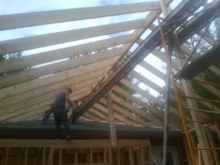 Rafters going up over a new addition with a worker on the wall in Otterbein