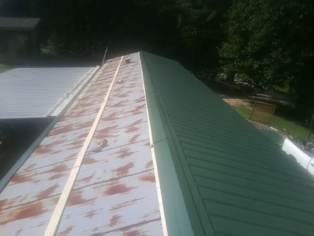 Old rusted panels beside newly installed green metal roofing — Wind Damage Roof Repair by Roofing Brothers in Otterbein