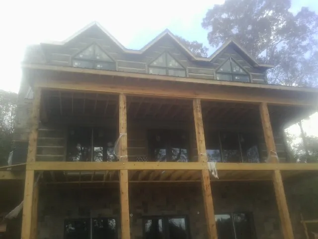 Dormers and porch framing on a large log home under construction — Roof Coating work by our crew in Otterbein