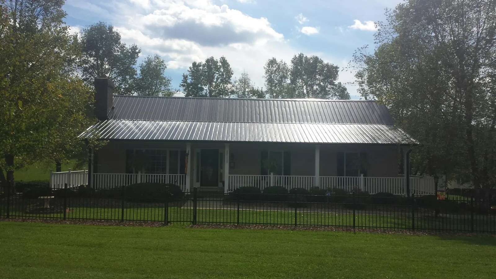 Gray metal roof on a brick ranch with a full width front porch — Gutter Guard Installation work by our crew in Otterbein