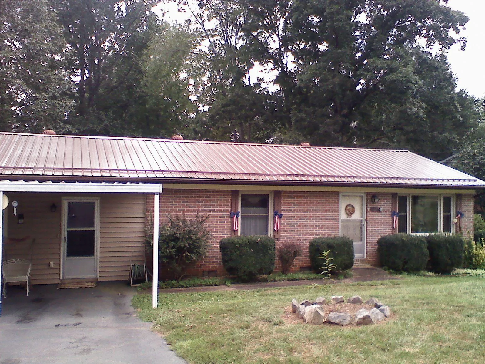 Bronze metal roof and carport on a brick ranch home — Roof Repair work by our crew in Otterbein