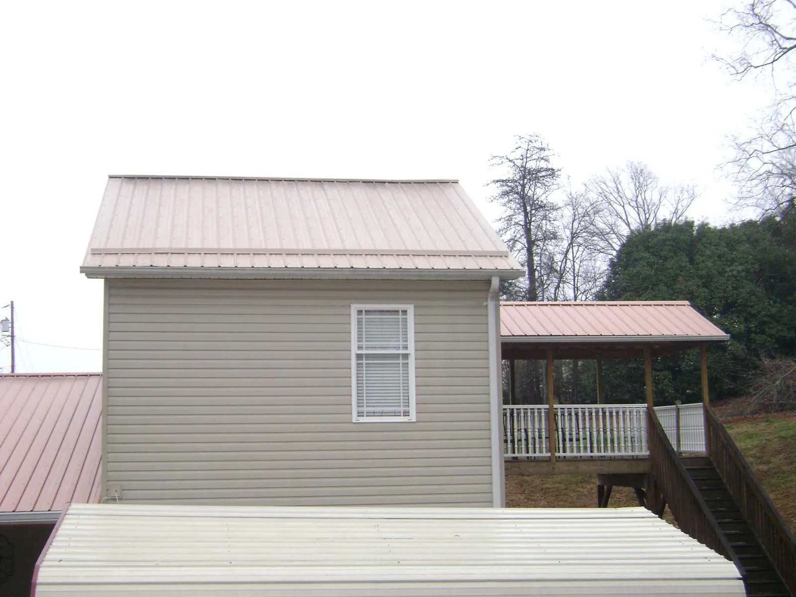 Tan metal roofs on a two story addition and attached porch, from a Roof Replacement job in Otterbein