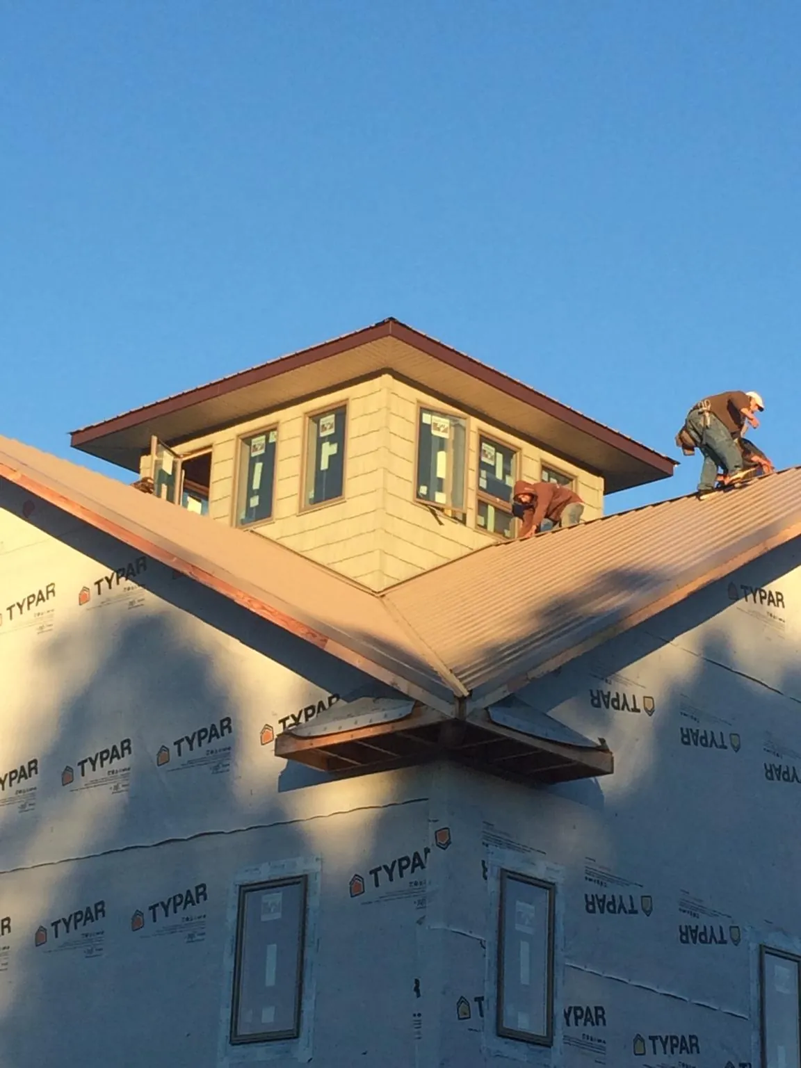 Roofers working around a rooftop cupola on a new metal roof at sunset — Roof Waterproofing in Otterbein by Roofing Brothers